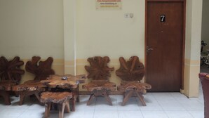 Una habitación con una puerta de madera que lleva el número 7, un cartel con URLs y una disposición de asientos con un banco de madera único.