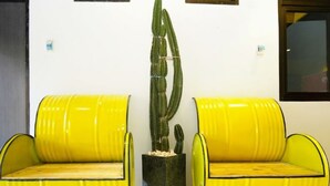 Two yellow armchairs with black legs, a tall cactus in a black pot, and a white wall with two small windows. - I Cloud Residence (Surabaya)