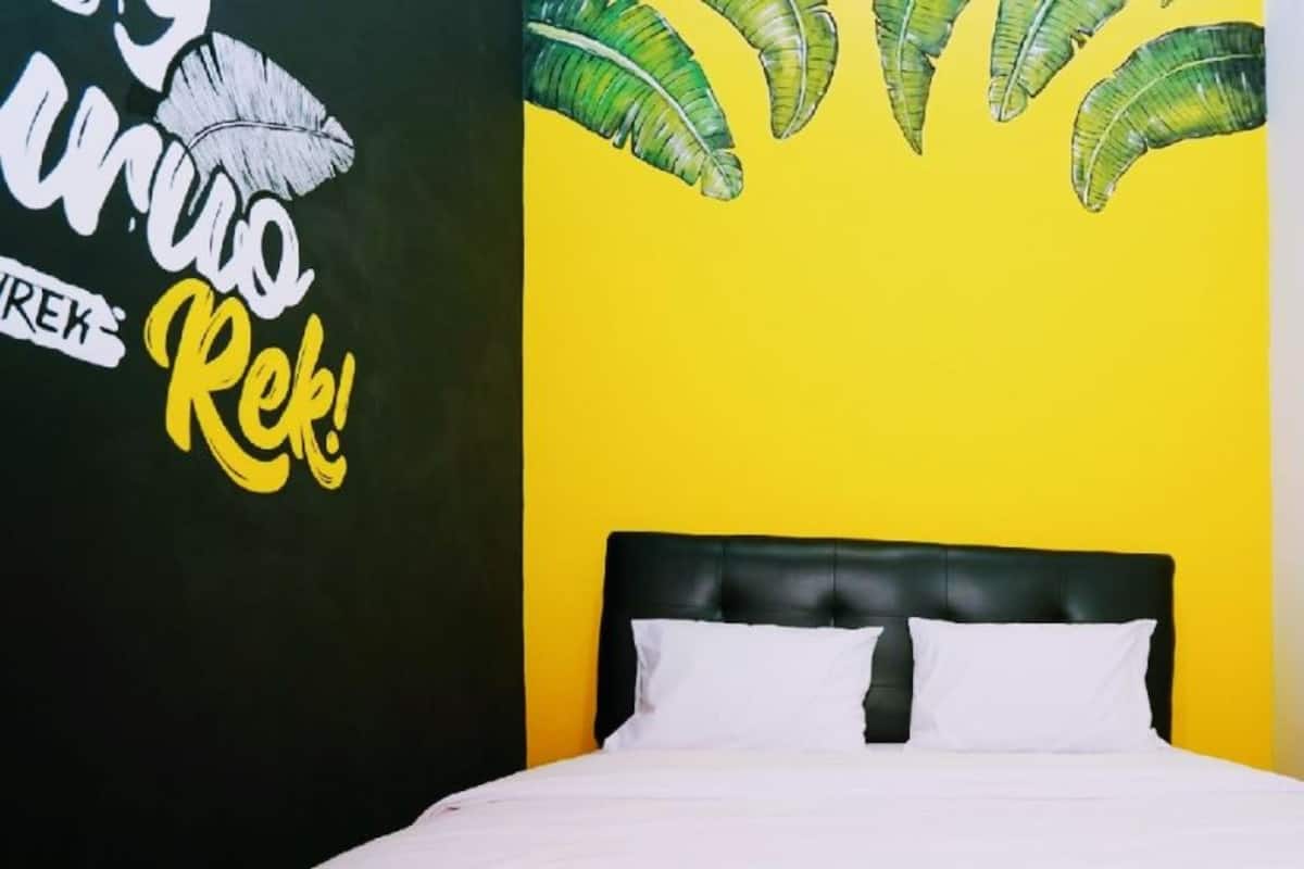 A bed with a black headboard and white pillows against a yellow wall.