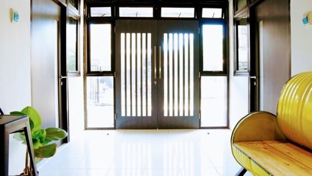 A hallway with a large door, a yellow bench, and a potted plant. - I Cloud Residence (Surabaya)