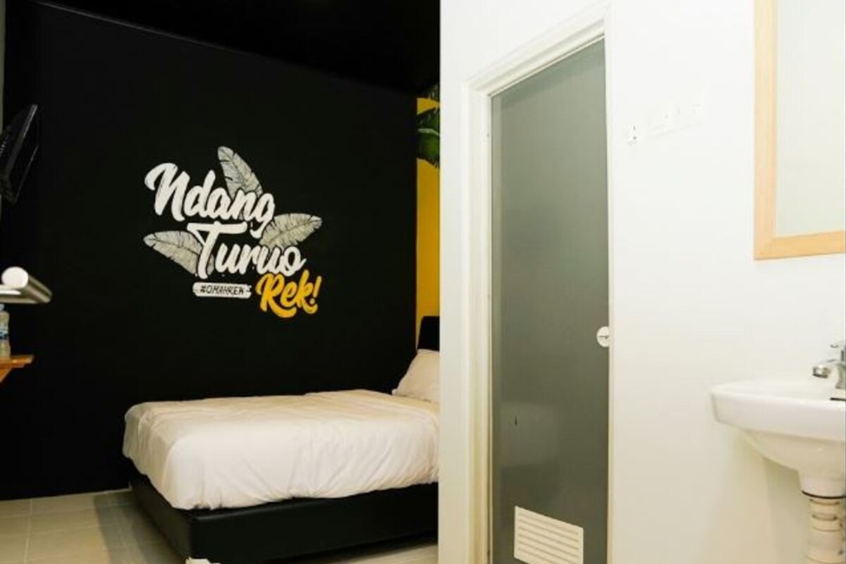 Un dormitorio con cama, una pared con una frase motivacional, una puerta y un baño con lavabo.