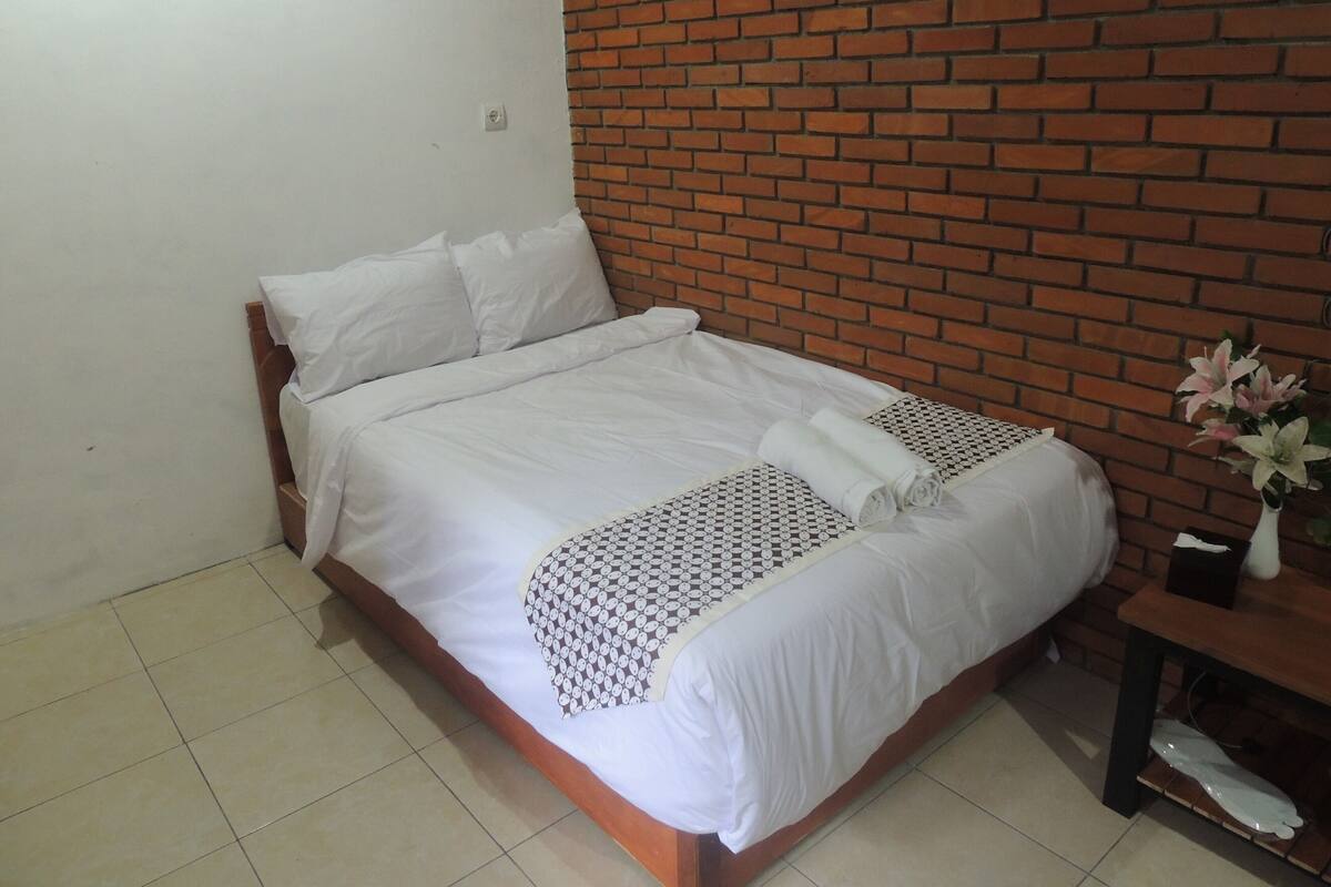 A neatly made bed with white linens and a decorative pillow.