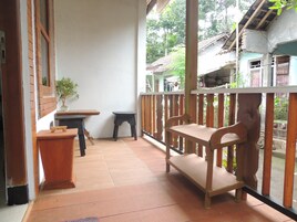 Un espacio al aire libre techado con un banco de madera, una mesa pequeña y una planta en maceta.