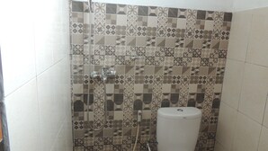 Ein Badezimmer mit gemusterten Fliesen, einer Toilette und einer Dusche inklusive Handbrause.
