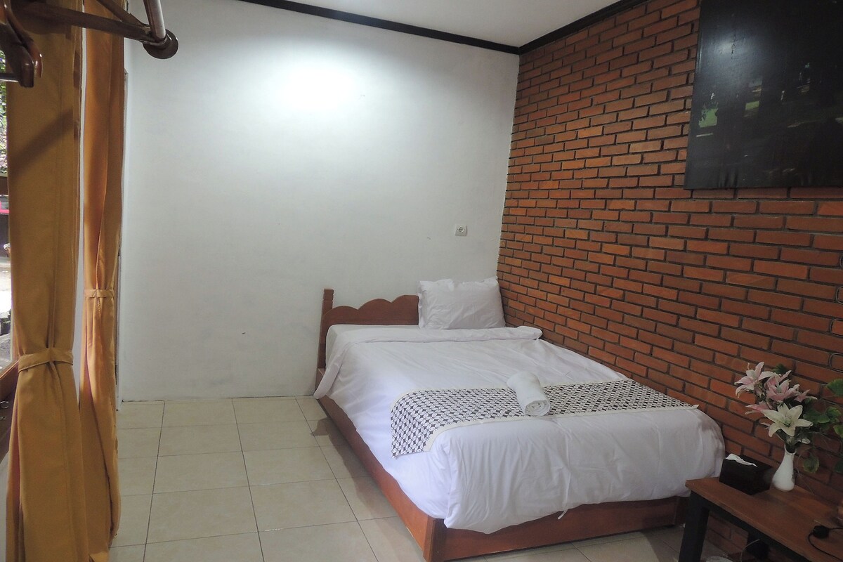 A neatly made bed with white linens, a wooden headboard, and a brick-patterned wall.