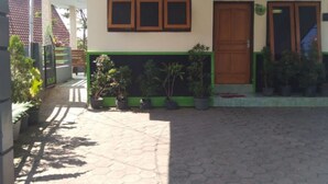 Une maison avec un patio carrelé, une porte en bois et des plantes en pot.