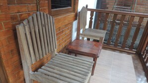 A wooden bench and table set against a brick wall, with a wooden railing in the background. - Penginapan Wardi Syariah Borobudur by Ndalem Beong (Borobudur)