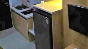 Une cuisine de taille réduite, équipée d’un évier, d’une cuisinière et d’un petit réfrigérateur.