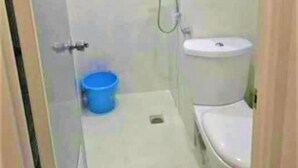 Une petite salle de bain avec des toilettes, un lavabo et un seau bleu.