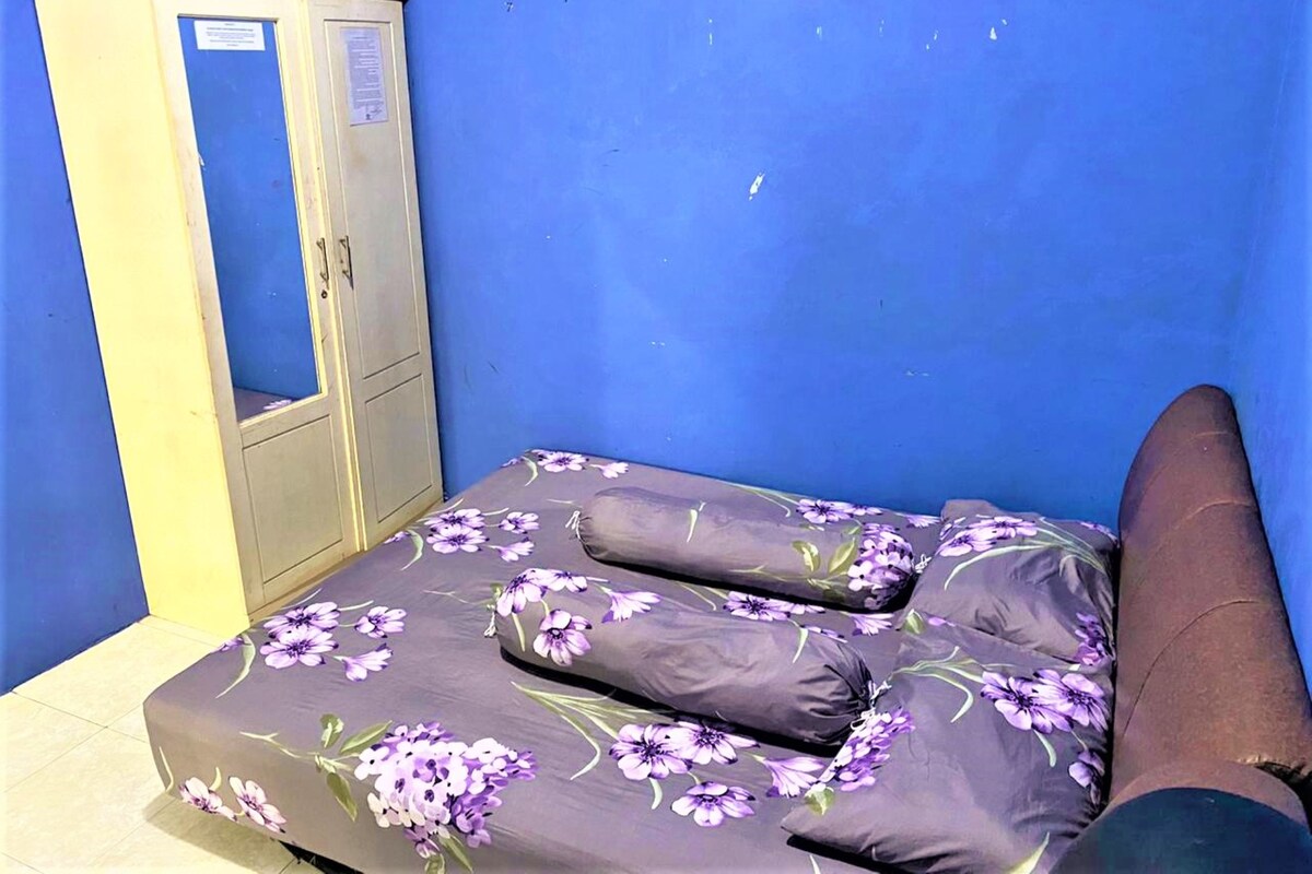 A small room with a bed, a wardrobe, and a blue wall.