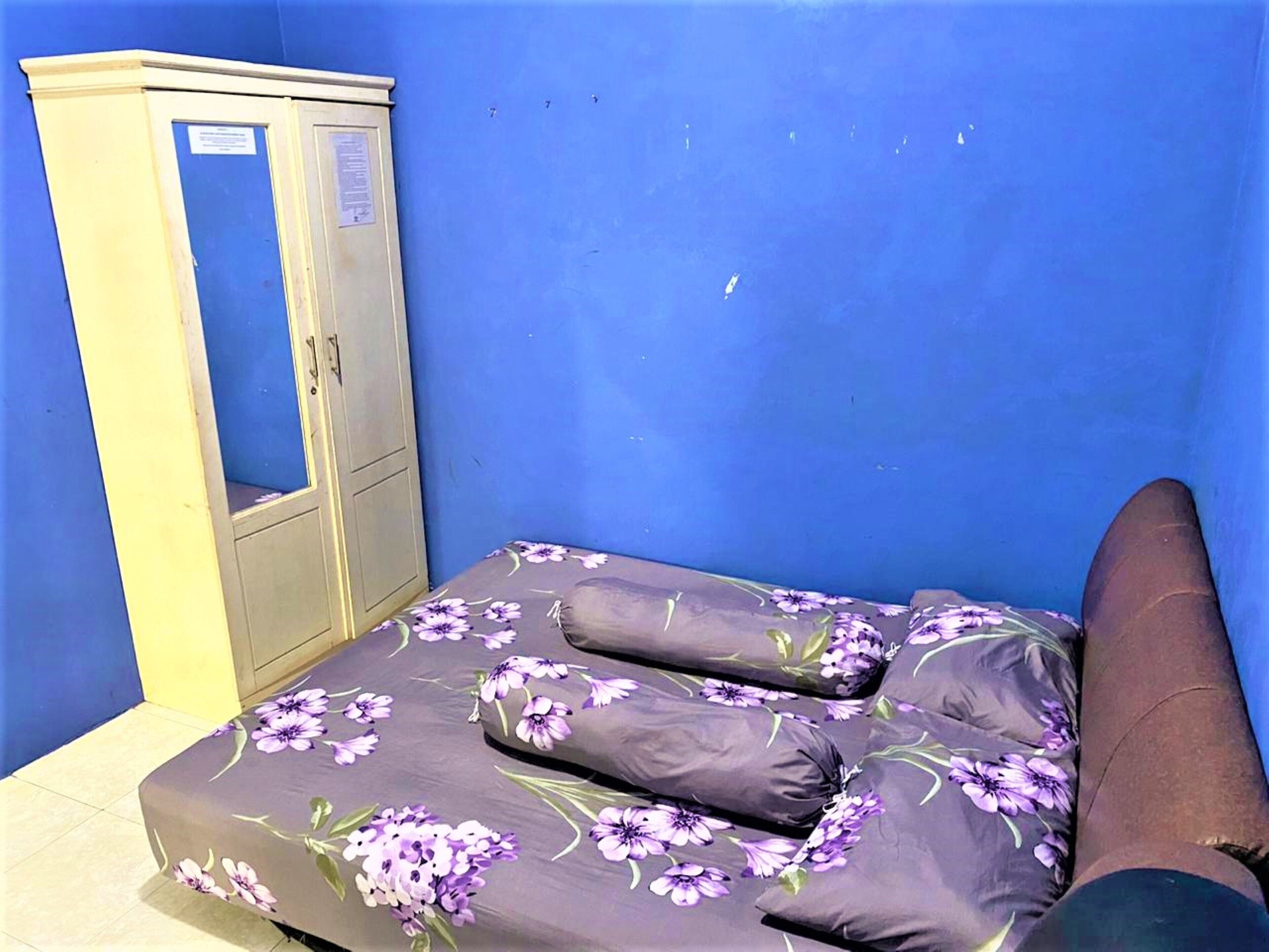Una habitación con una cama, un armario y una pared azul.