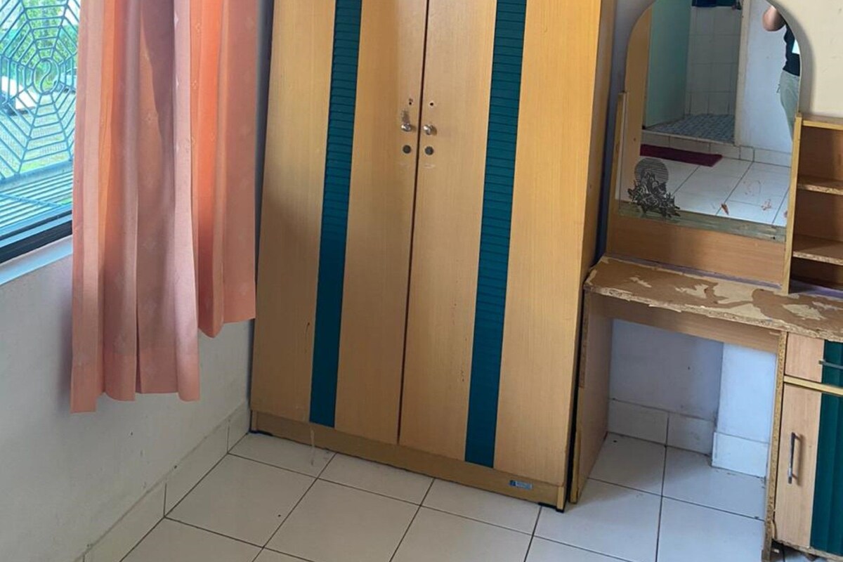 A room with a wardrobe, a mirror, and a window with a curtain.