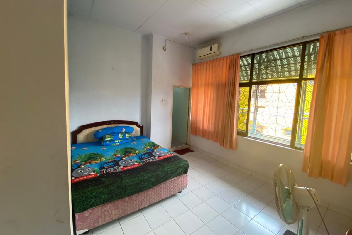 Un dormitorio con cama, ventilador y ventana con cortinas.