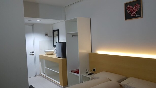 A modern bedroom with a bed, bedside table, and a mirror. - Grand Sentraland Karawang by Gkit Room (Karawang)