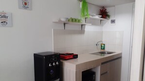 A compact kitchen with a refrigerator, a sink, and a small countertop. - Grand Sentraland Karawang by Gkit Room (Karawang)