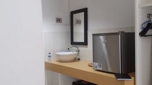 A modern bathroom with a white sink, a mirror, and a stainless steel refrigerator. - Grand Sentraland Karawang by Gkit Room (Karawang)