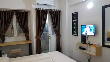 A hotel room with a bed, a desk, a television, and a window with curtains.
