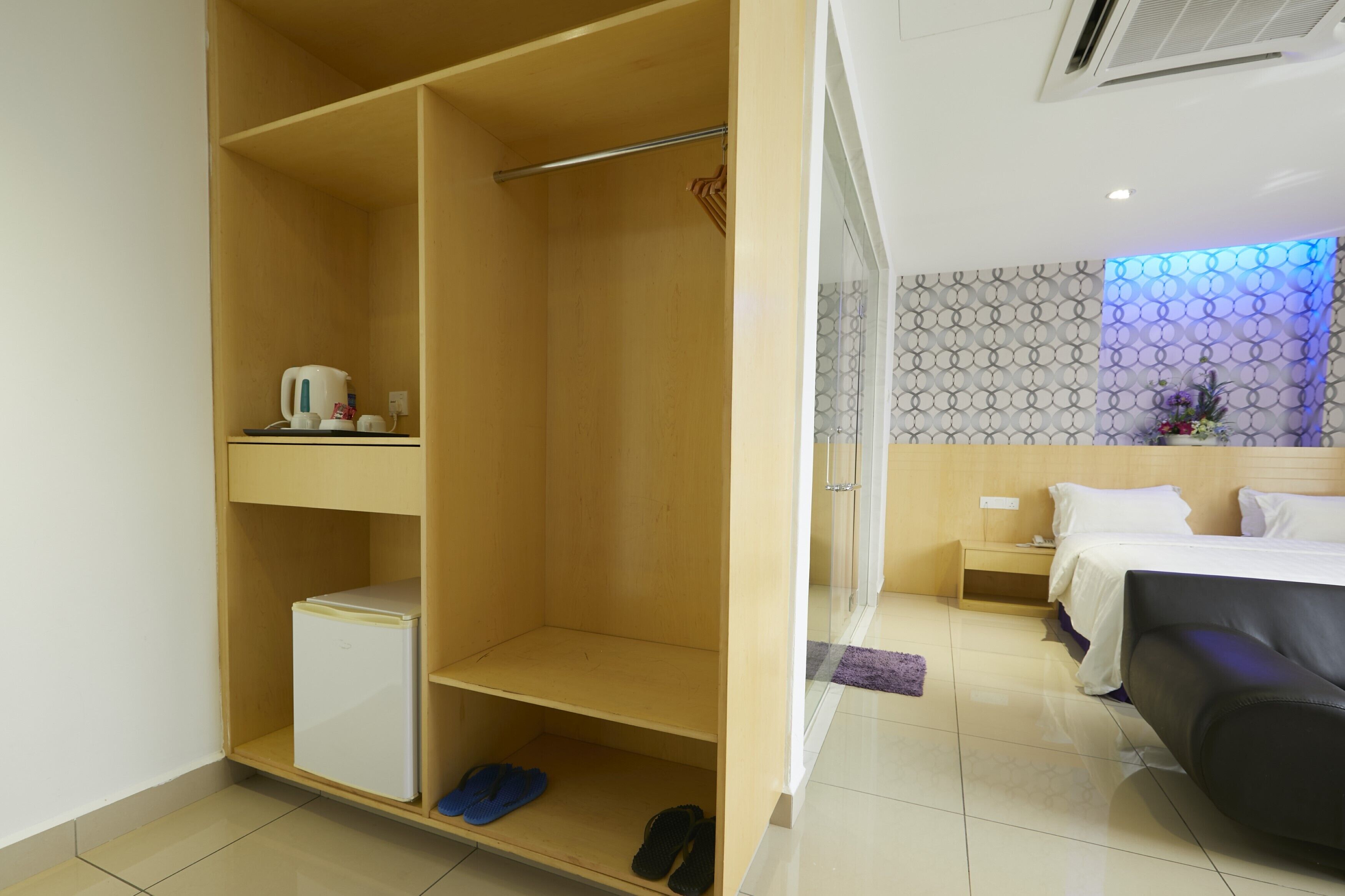 A hotel room with a wardrobe, a bed, a small bedside table, and a nightstand.