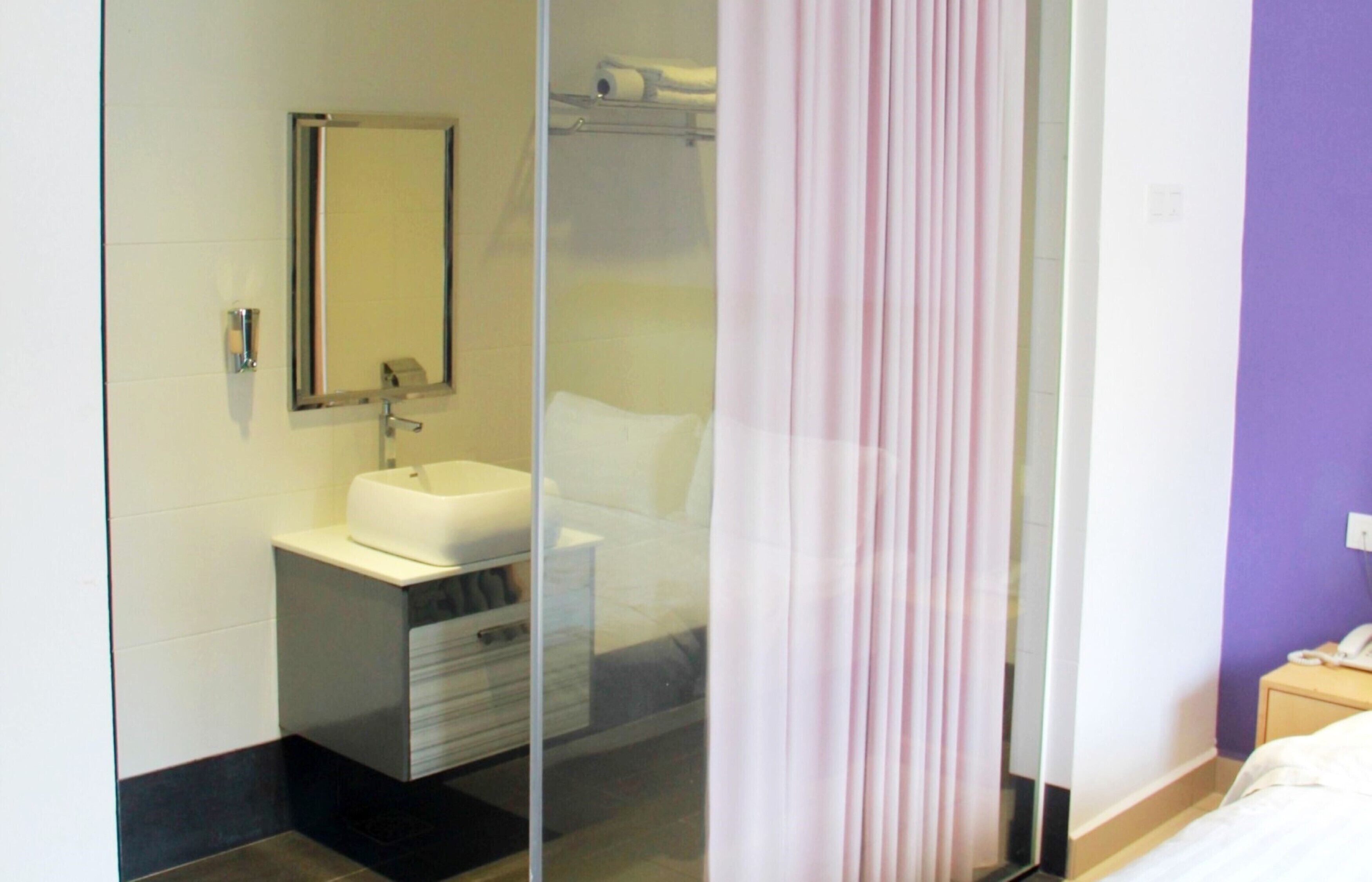 A modern bathroom with a glass shower enclosure, a white sink, and a mirror.