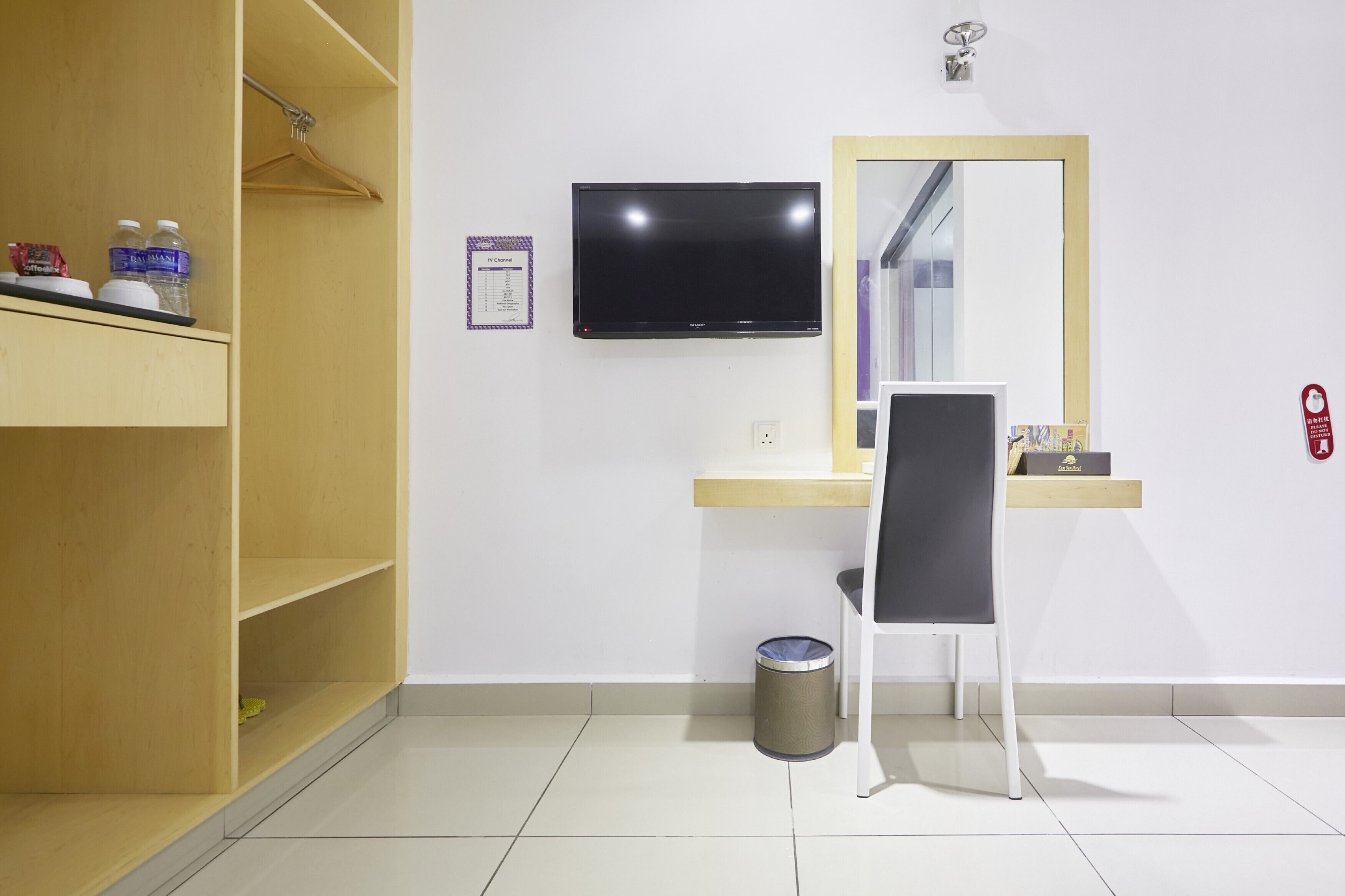 Habitació d'hotel amb un armari de fusta, un escriptori amb una cadira, una televisió, un mirall i un safataire.