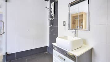 Ein modernes Badezimmer mit einem weißen Waschbecken, einem Spiegel und einer Duschkabine.