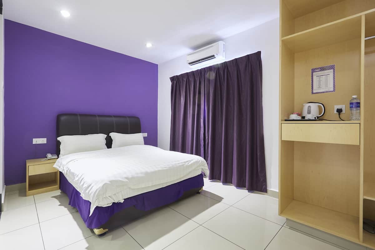 A bedroom with a bed, a nightstand, an air conditioner, a wooden shelf, and a window with curtains.