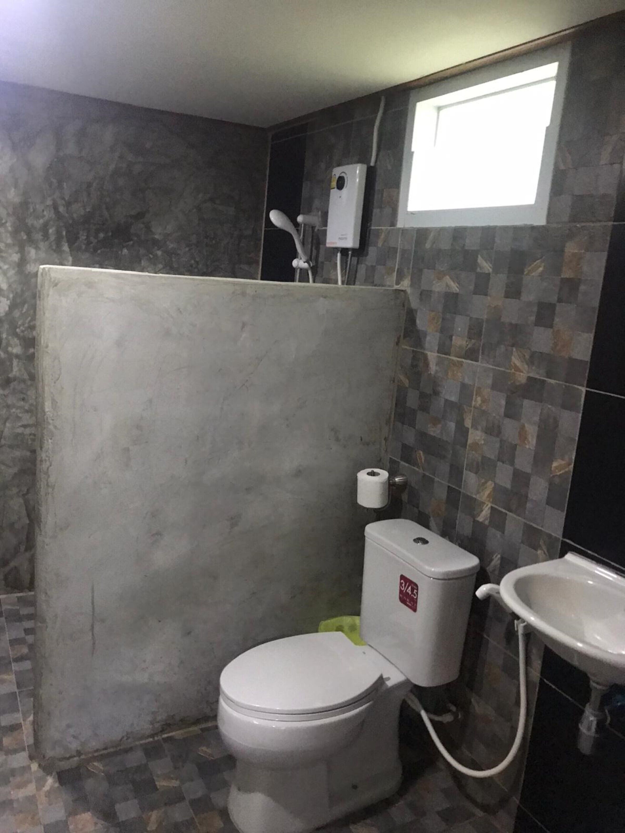 Une salle de bain comprenant des toilettes, un lavabo et un espace douche.