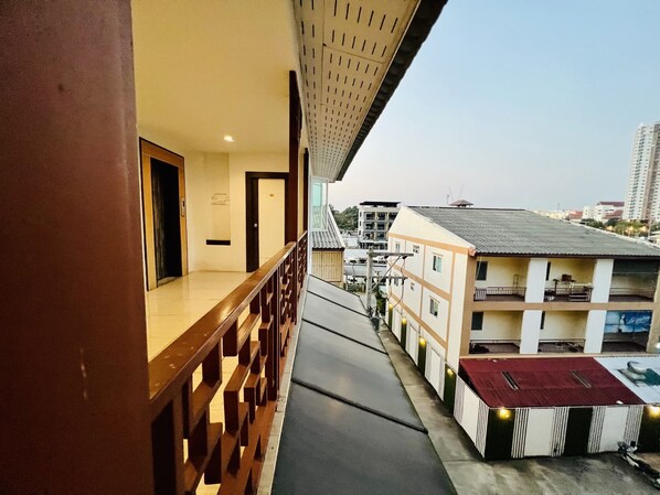 A balcony with a wooden railing overlooking a street with buildings.