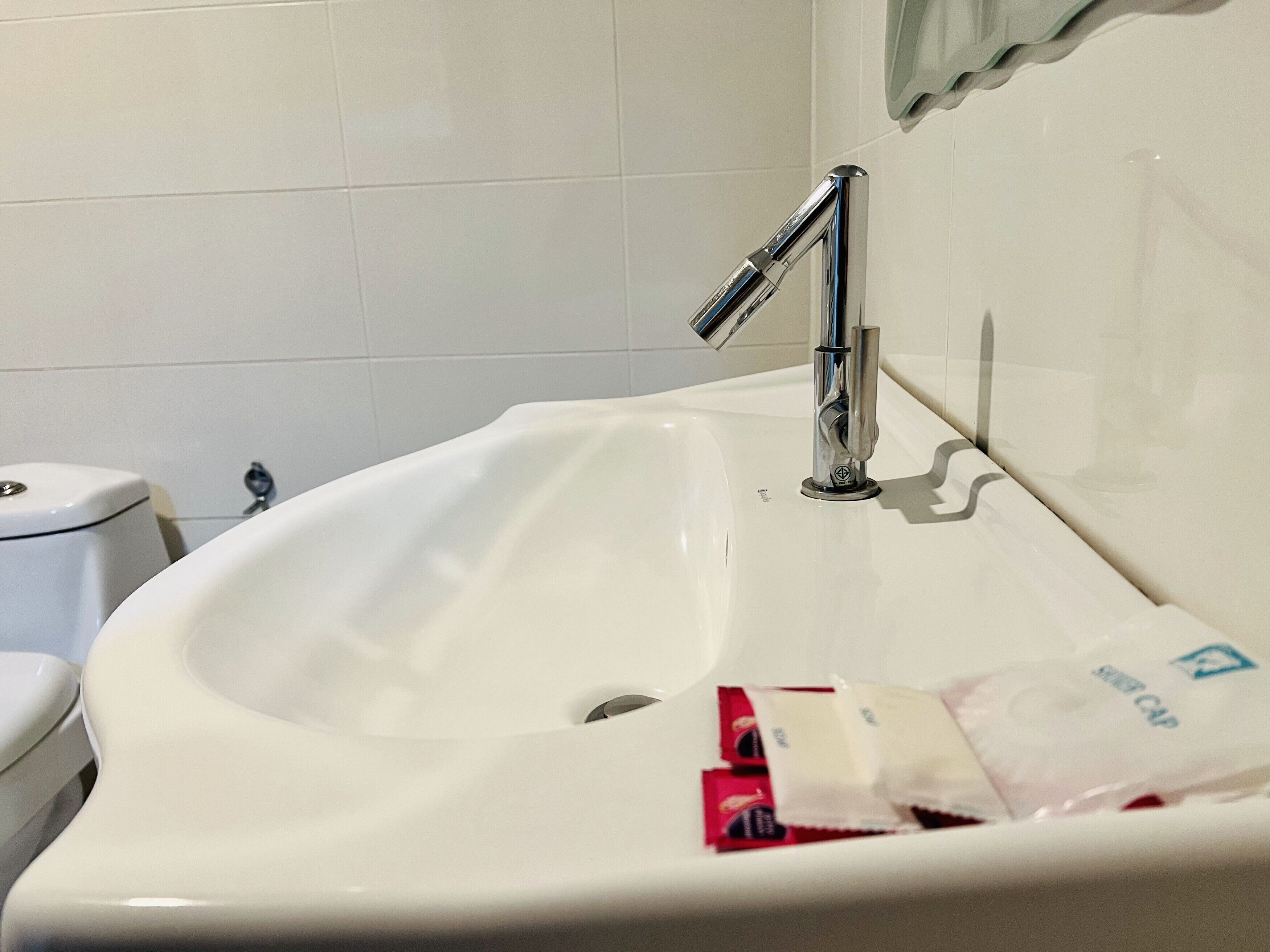 A bathroom with a white sink, chrome faucet, and a toilet.