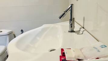 A bathroom with a white sink, chrome faucet, and a toilet.