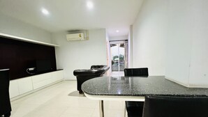 A modern kitchen with a black countertop, white cabinets, and a black chair. There is a window with a view of the outside. - INN Kham Apartment (Chiang Mai)