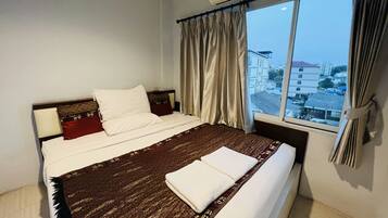 Une chambre d’hôtel avec un grand lit, une fenêtre avec des rideaux et un appareil de climatisation.
