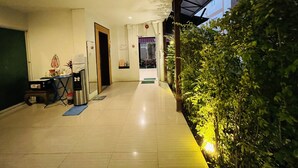 A hallway with a tiled floor, a desk with a chair, and a small plant area. - INN Kham Apartment (Chiang Mai)