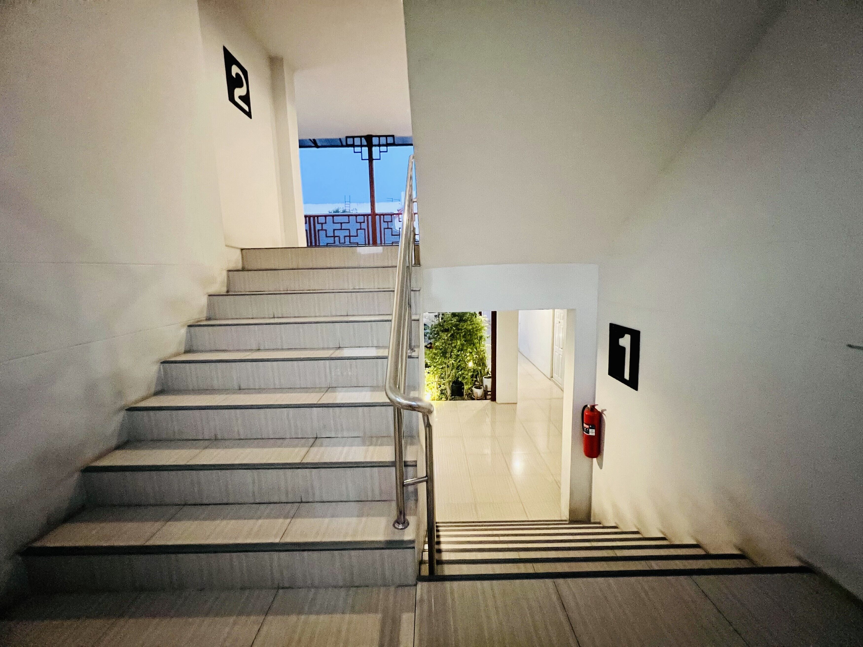 Una escalera con barandilla metálica que lleva a una puerta con el número 1.