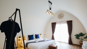 Un dormitorio moderno con cama, lámparas de noche, perchero colgante, planta en maceta y un reloj en la pared.