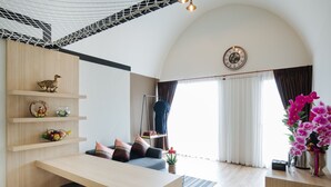 Una sala de estar moderna con una mesa de comedor de madera, un sofá con cojines, un pato decorativo y un jarrón de flores.