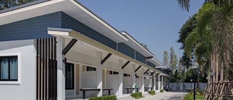 A modern building with a covered outdoor area, benches, and a pathway.