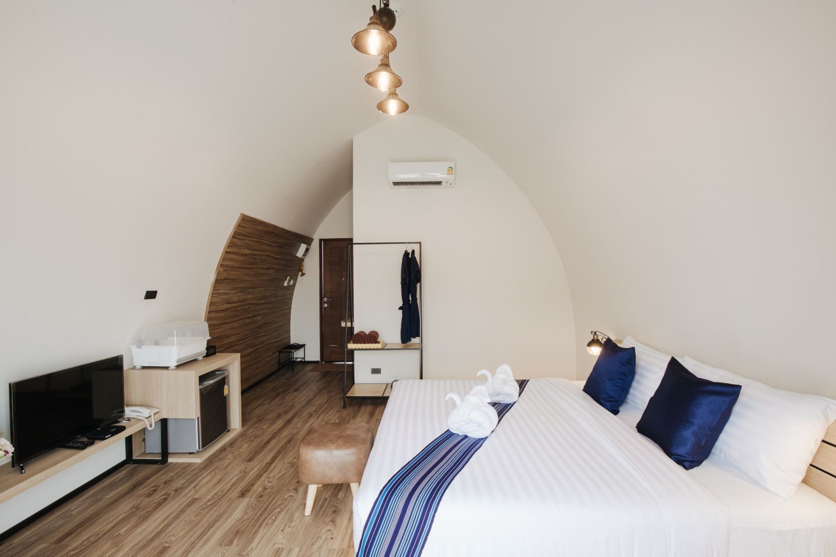 A hotel room with a bed, a TV, a desk, a wardrobe, and a mirror.