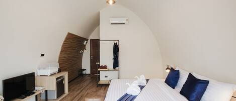 A hotel room with a bed, a TV, a desk, a wardrobe, and a mirror.