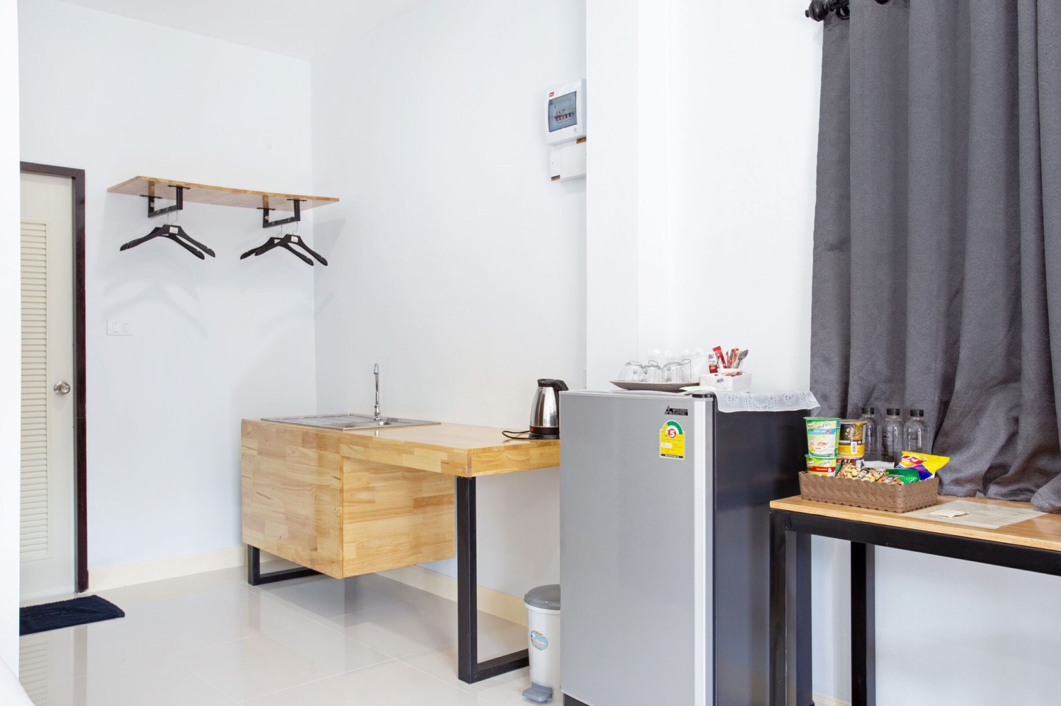 A compact kitchenette with a wooden countertop, a sink, a refrigerator, and a small table with snacks.
