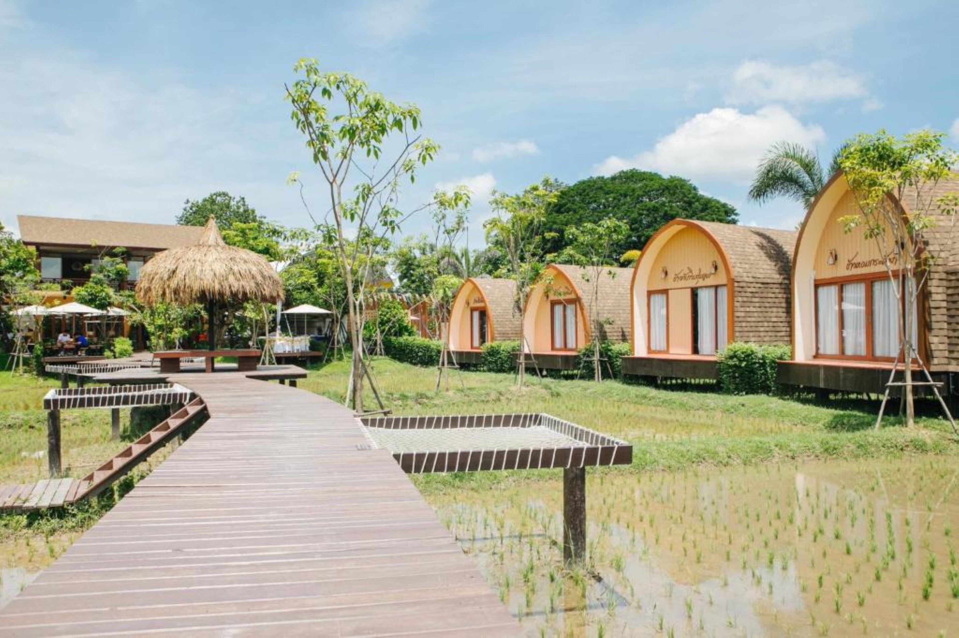 Ein Resort mit Holzstegen, Hütten mit Strohdächern und einem Gewässer.