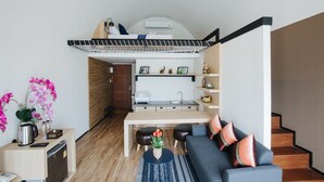 Un espacio habitable compacto con kitchenette, sofá, mesa de comedor y literas.