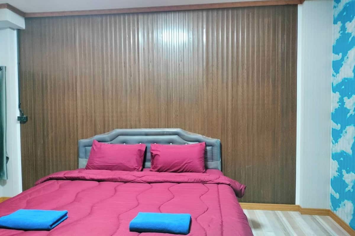 A bedroom with a bed, a wooden panel wall, and a blue wall with a cloud pattern.