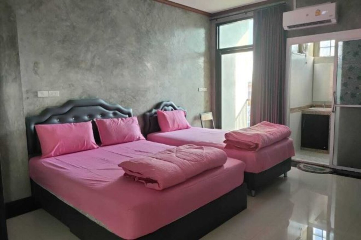 A double bed with a headboard, a bedside table, and a window with curtains.