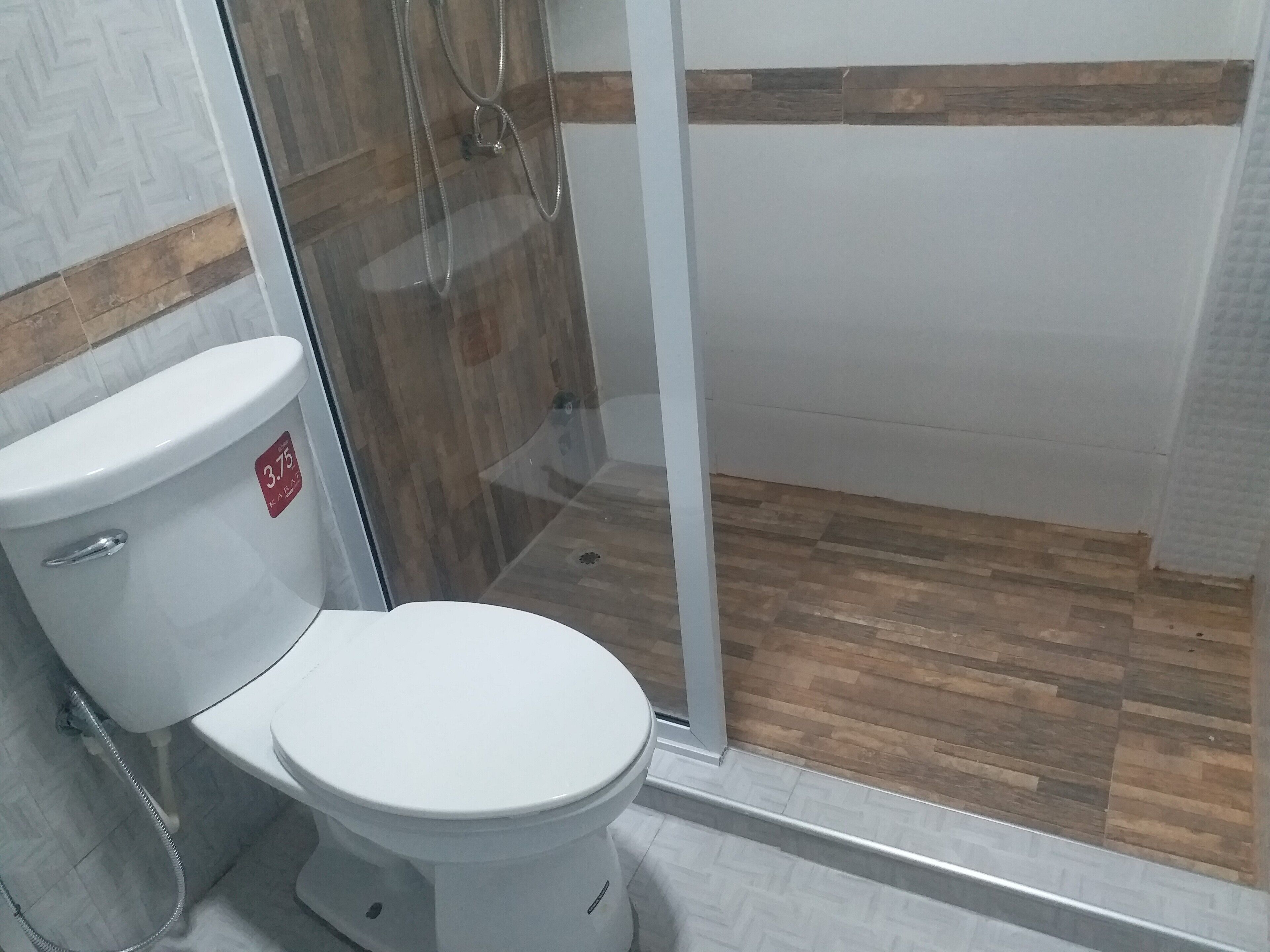 Une salle de bain comprenant des toilettes, un espace douche et un plancher en bois.