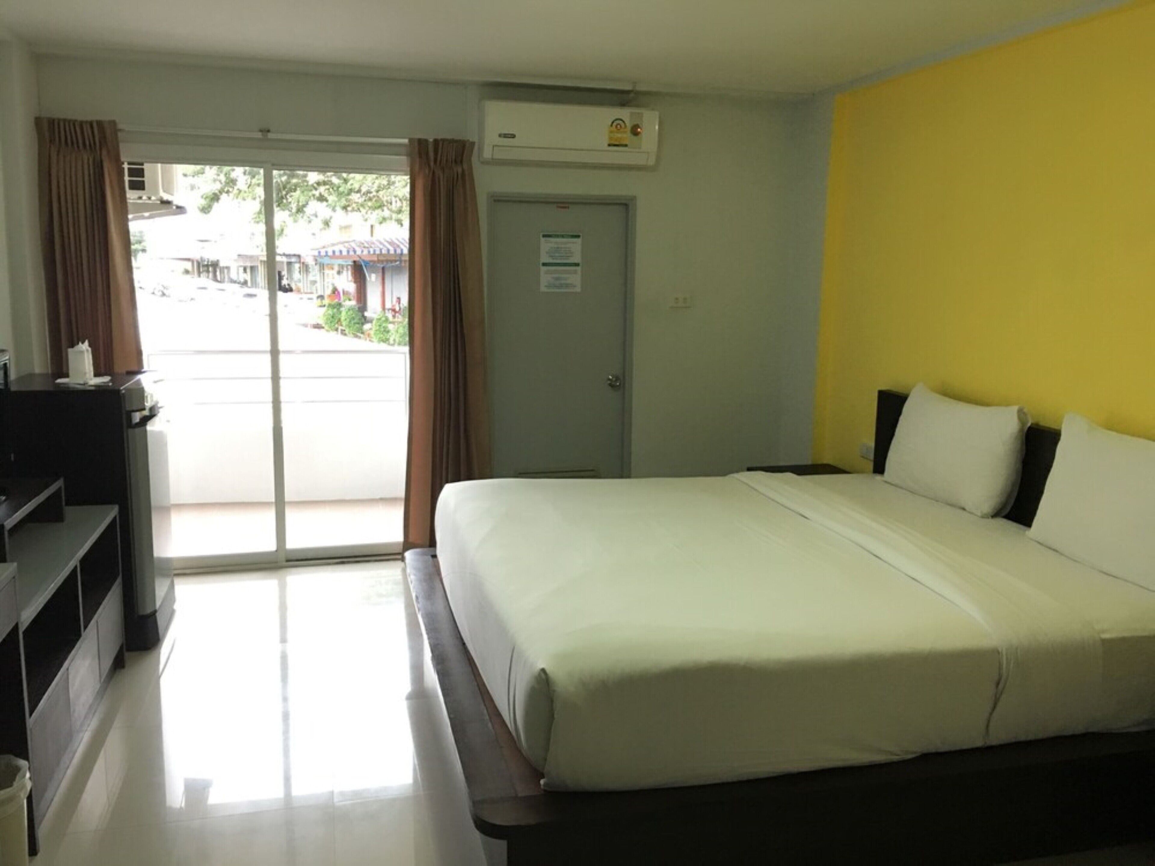 A hotel room with a bed, a desk, and a door to the outside.