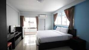 A modern hotel room with a bed, a TV, a desk, and a view of the outside.