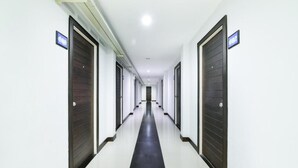 A long, narrow hallway with dark wooden doors on both sides and a black carpet running down the center.