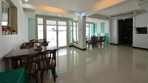 A spacious dining area with multiple tables and chairs, large windows, and a clean, modern interior.