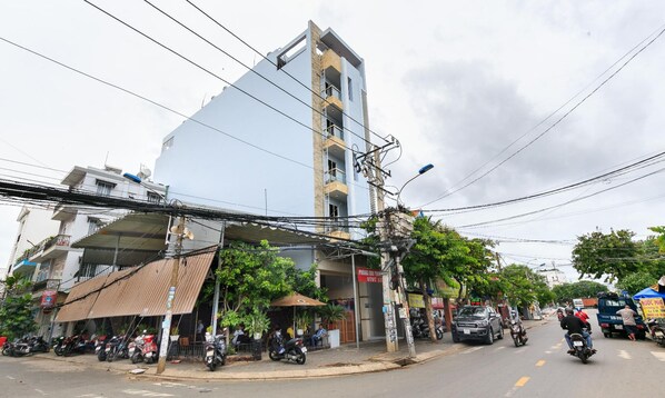 Un edificio de varios pisos con diseño moderno, que cuenta con balcones y una combinación de espacios comerciales y residenciales.